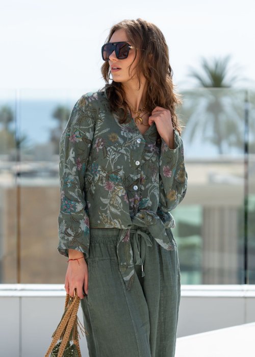 Lniana koszula damska w kolorze khaki z botanicznym printem w pastelowych barwach, o luźnym asymetrycznym kroju, zestawiona z lnianymi spodniami w tym samym odcieniu.