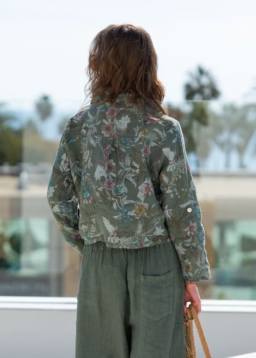 Lniana koszula damska w kolorze khaki z botanicznym printem w pastelowych barwach, o luźnym asymetrycznym kroju, zestawiona z lnianymi spodniami w tym samym odcieniu.