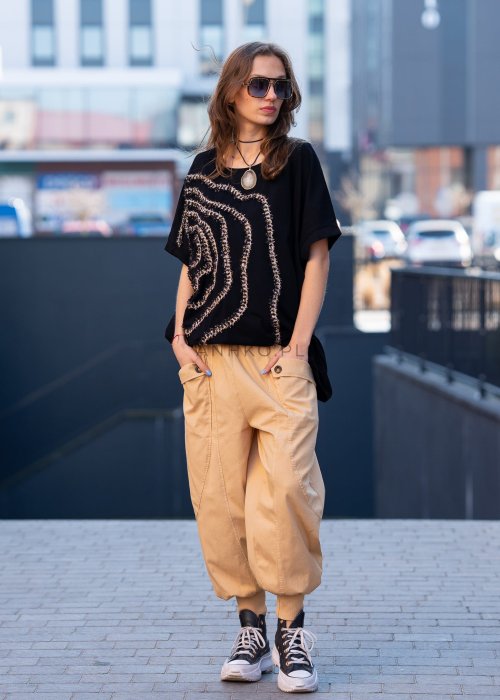 Czarna bluzka oversize damska z ozdobnym haftem 3D w kształcie spirali. Stylizacja casual z jasnymi spodniami i dodatkami w miejskim stylu.