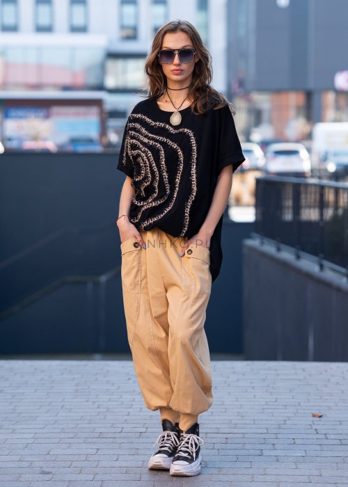 Czarna bluzka oversize damska z ozdobnym haftem 3D w kształcie spirali. Stylizacja casual z jasnymi spodniami i dodatkami w miejskim stylu.