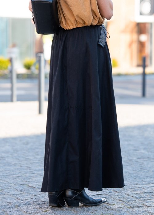 Czarna spódnica maxi o rozkloszowanym fasonie z miękko układającego się materiału. Model z wysokim stanem i szerokim paskiem podkreśla talię, tworząc elegancką i kobiecą sylwetkę idealną zarówno do casualowych, jak i bardziej wyrazistych stylizacji.