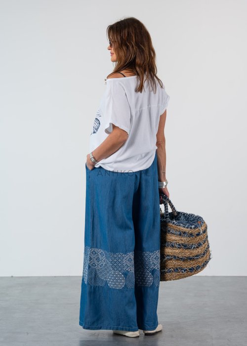 Niebieskie spodnie damskie wide leg z szerokimi nogawkami i ozdobnym panelem z wzorem, luźny fason w stylowej, casualowej stylizacji.