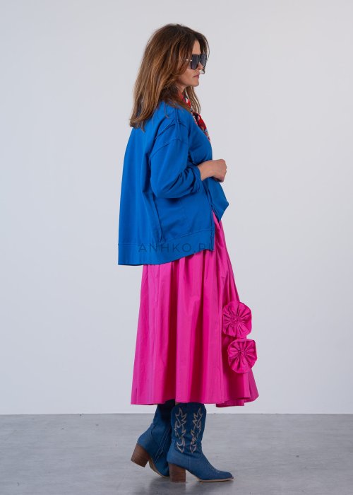 Damska bluza oversize w intensywnym niebieskim kolorze z długim rękawem i okrągłym dekoltem. Stylizacja zestawiona z różową spódnicą i okularami przeciwsłonecznymi.