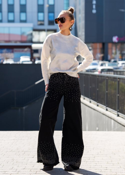Sweter damski o luźnym, lekko oversize’owym fasonie z miękkiej, delikatnie puszystej dzianiny w kolorze kremowej bieli, z subtelnym, srebrzystym połyskiem na powierzchni, okrągłym dekoltem wykończonym prążkowaną lamówką