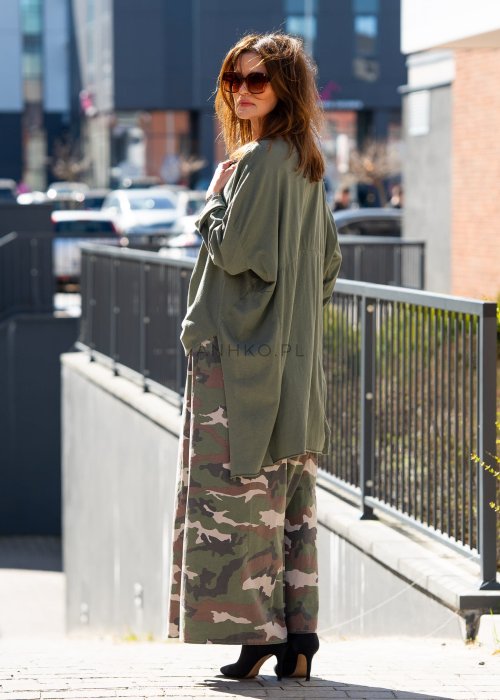 Ciemnozielona bluza damska oversize z asymetrycznym dołem i długim rękawem. Model o luźnym kroju pokazany w stylizacji z długą spódnicą moro w miejskim looku.