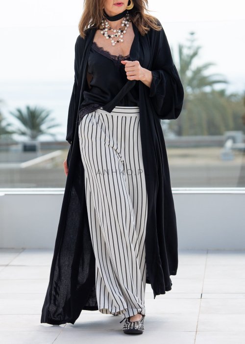 Czarne kimono damskie maxi o długim, lejącym fasonie z bufiastymi rękawami. Stylizacja z topem i szerokimi spodniami w kontrastowe paski.