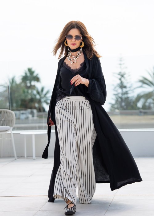Czarne kimono damskie maxi o długim, lejącym fasonie z bufiastymi rękawami. Stylizacja z topem i szerokimi spodniami w kontrastowe paski.