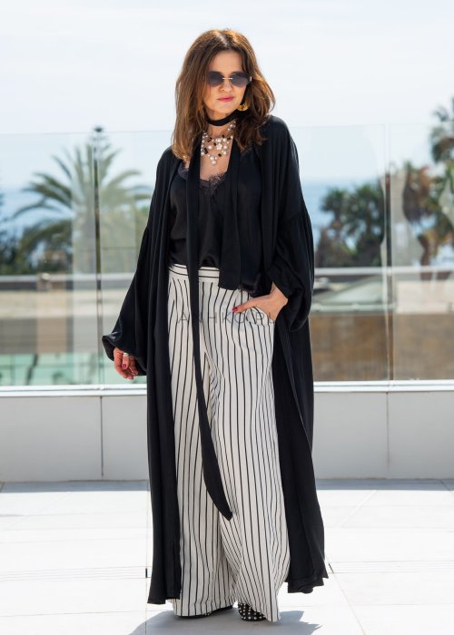 Czarne kimono damskie maxi o długim, lejącym fasonie z bufiastymi rękawami. Stylizacja z topem i szerokimi spodniami w kontrastowe paski.