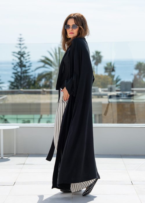 Czarne kimono damskie maxi o długim, lejącym fasonie z bufiastymi rękawami. Stylizacja z topem i szerokimi spodniami w kontrastowe paski.
