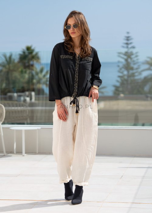 Śmietankowe spodnie lniane damskie o luźnym kroju RelaxFit z elastycznym pasem i troczkiem, stylizowane z czarną koszulą i botkami w eleganckim, minimalistycznym looku.