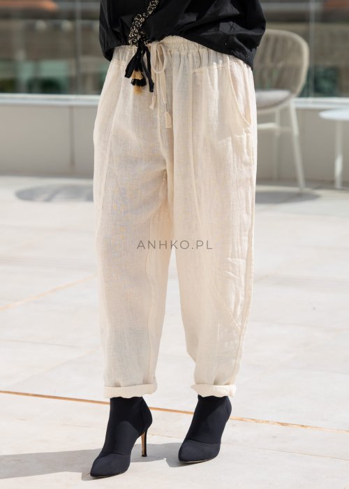 Śmietankowe spodnie lniane damskie o luźnym kroju RelaxFit z elastycznym pasem i troczkiem, stylizowane z czarną koszulą i botkami w eleganckim, minimalistycznym looku.