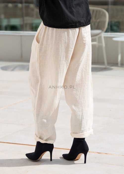 Śmietankowe spodnie lniane damskie o luźnym kroju RelaxFit z elastycznym pasem i troczkiem, stylizowane z czarną koszulą i botkami w eleganckim, minimalistycznym looku.