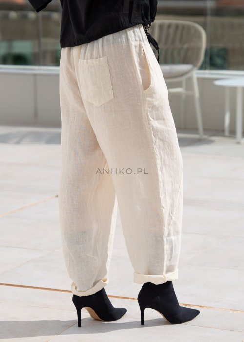 Śmietankowe spodnie lniane damskie o luźnym kroju RelaxFit z elastycznym pasem i troczkiem, stylizowane z czarną koszulą i botkami w eleganckim, minimalistycznym looku.