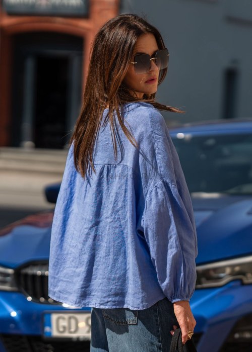 Niebieska koszula lniana oversize z dekoltem V i guzikami, stylizowana z jeansami.