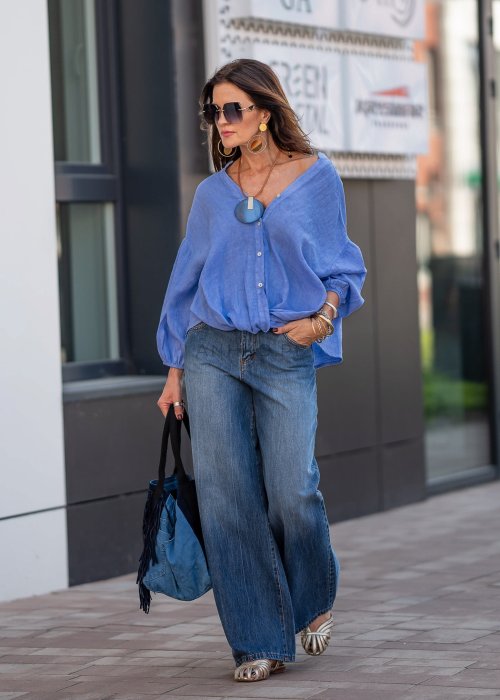 Niebieska koszula lniana oversize z dekoltem V i guzikami, stylizowana z jeansami.