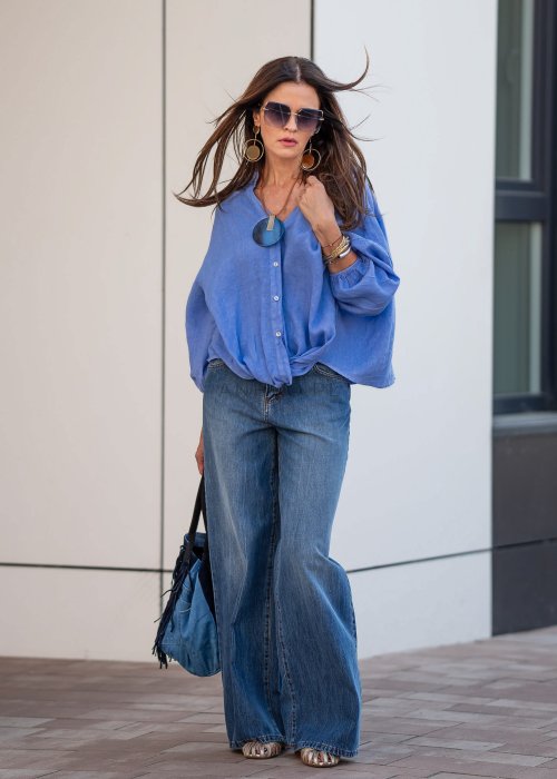 Niebieska koszula lniana oversize z dekoltem V i guzikami, stylizowana z jeansami.