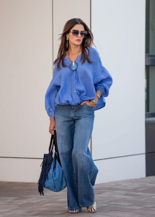 Niebieska koszula lniana oversize z dekoltem V i guzikami, stylizowana z jeansami.