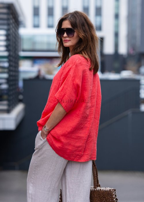 Koralowa lniana bluzka oversize ze ściągaczem u dołu, stylizowana z biżuterią i miejskim outfitem w energetycznym wydaniu.
