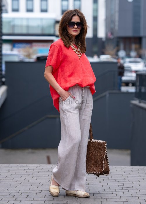 Koralowa lniana bluzka oversize ze ściągaczem u dołu, stylizowana z biżuterią i miejskim outfitem w energetycznym wydaniu.