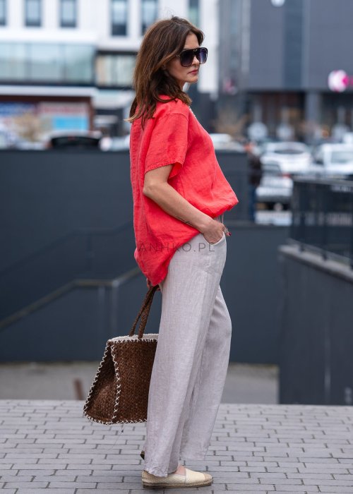 Koralowa lniana bluzka oversize ze ściągaczem u dołu, stylizowana z biżuterią i miejskim outfitem w energetycznym wydaniu.