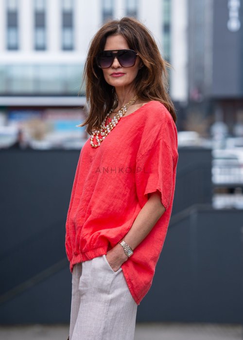 Koralowa lniana bluzka oversize ze ściągaczem u dołu, stylizowana z biżuterią i miejskim outfitem w energetycznym wydaniu.