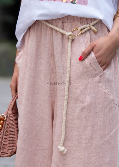 Jasnoróżowe lniane spodnie damskie z szeroką nogawką i elastycznym pasem ze sznurkiem. Stylizacja casual z białą bluzką i balerinami.