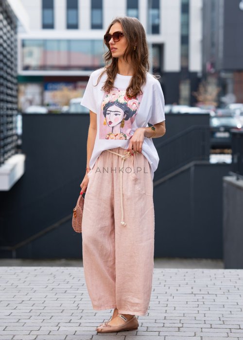 Jasnoróżowe lniane spodnie damskie z szeroką nogawką i elastycznym pasem ze sznurkiem. Stylizacja casual z białą bluzką i balerinami.