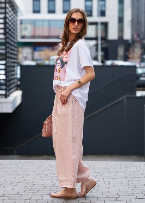 Jasnoróżowe lniane spodnie damskie z szeroką nogawką i elastycznym pasem ze sznurkiem. Stylizacja casual z białą bluzką i balerinami.