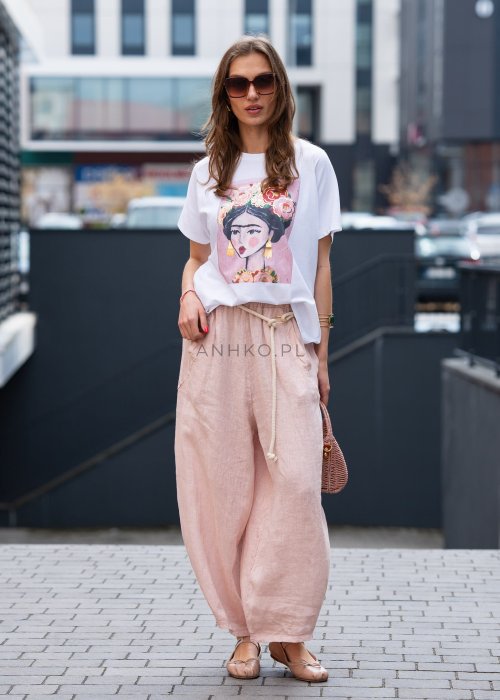 Jasnoróżowe lniane spodnie damskie z szeroką nogawką i elastycznym pasem ze sznurkiem. Stylizacja casual z białą bluzką i balerinami.