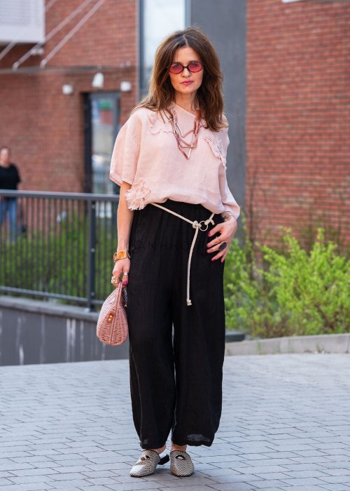 Czarne lniane spodnie damskie z szeroką nogawką i elastycznym pasem ze sznurkiem. Stylizacja casual z lekką bluzką i balerinami w miejskim wydaniu.