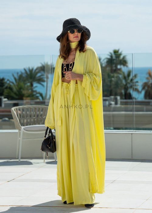 Żółte spodnie damskie z szeroką, lejącą nogawką i elastycznym pasem, stylizowane z czarnym topem w nowoczesnym, miejskim stylu.