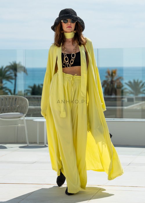 Żółte spodnie damskie z szeroką, lejącą nogawką i elastycznym pasem, stylizowane z czarnym topem w nowoczesnym, miejskim stylu.