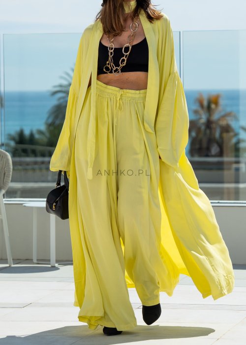 Żółte spodnie damskie z szeroką, lejącą nogawką i elastycznym pasem, stylizowane z czarnym topem w nowoczesnym, miejskim stylu.