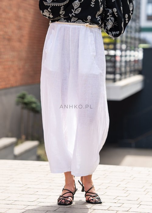 Białe lniane spodnie damskie z szeroką nogawką i elastycznym pasem ze sznurkiem, stylizowane z czarną haftowaną bluzką i sandałkami na obcasie.