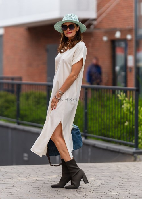 Śmietankowa sukienka midi z dekoltem V i krótkim rękawem, luźny fason z bocznym rozcięciem w stylizacji z botkami i kapeluszem.