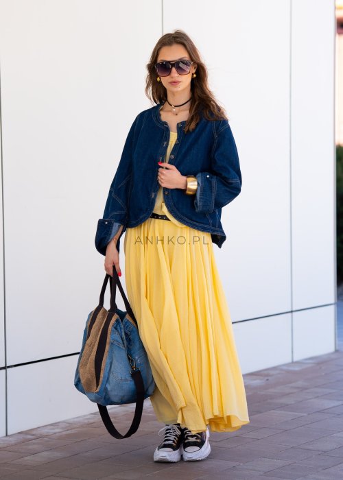 Krótka kurtka jeansowa damska bez kołnierza z ozdobnymi przeszyciami i napami, stylizowana z żółtą sukienką i biżuterią.