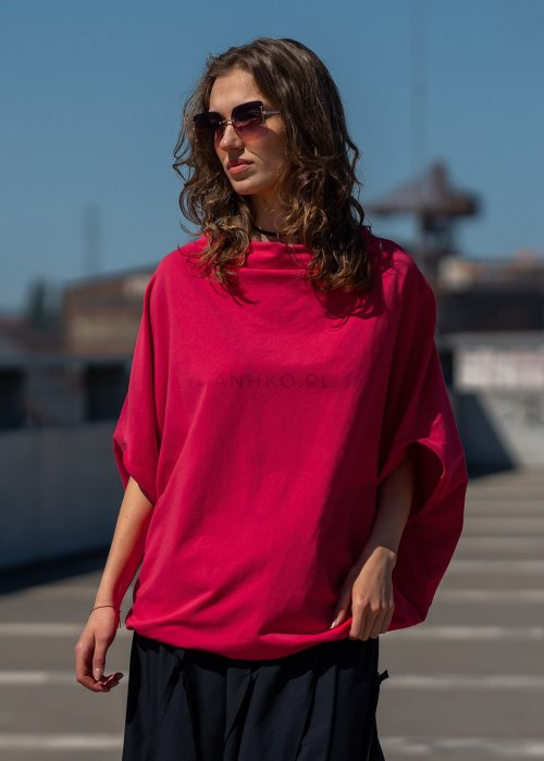 Czerwona bluzka damska oversize z rękawami typu nietoperz i szerokim dekoltem, zestawiona z czarną spódnicą w nowoczesnej stylizacji miejskiej.