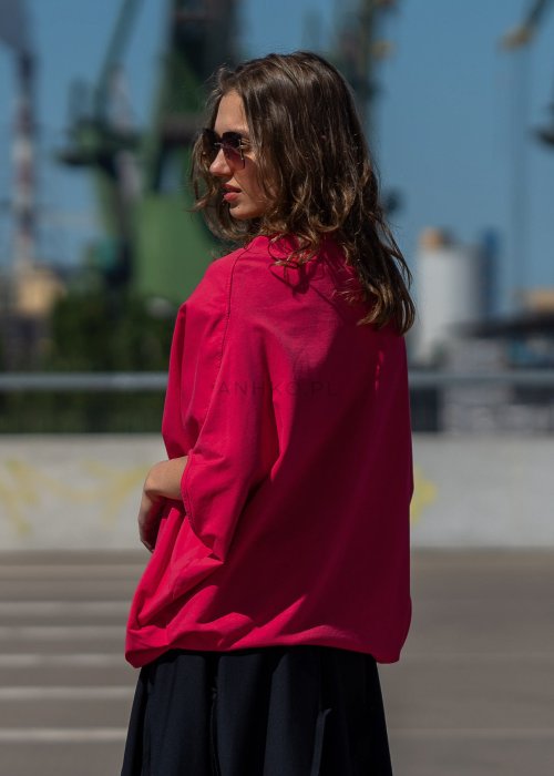 Czerwona bluzka damska oversize z rękawami typu nietoperz i szerokim dekoltem, zestawiona z czarną spódnicą w nowoczesnej stylizacji miejskiej.