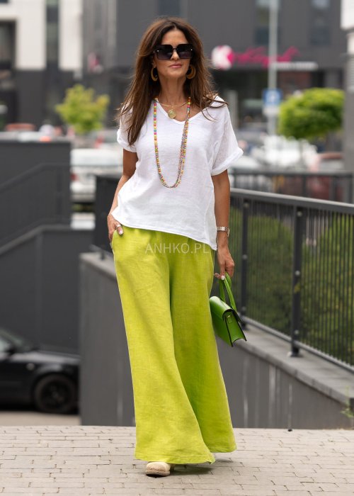 Limonkowe lniane spodnie damskie z bardzo szeroką nogawką i gumą w pasie, model z kieszeniami po bokach w swobodnej miejskiej stylizacji.