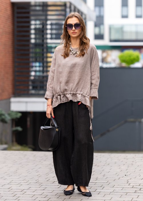 Czarne lniane spodnie damskie z szeroką nogawką i elastycznym pasem ze sznurkiem. Stylizacja casual z lekką bluzką i balerinami w miejskim wydaniu.