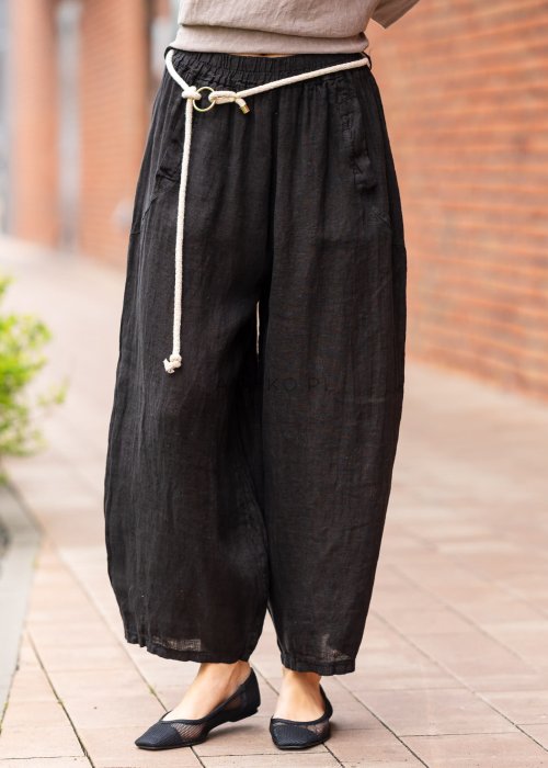 Czarne lniane spodnie damskie z szeroką nogawką i elastycznym pasem ze sznurkiem. Stylizacja casual z lekką bluzką i balerinami w miejskim wydaniu.