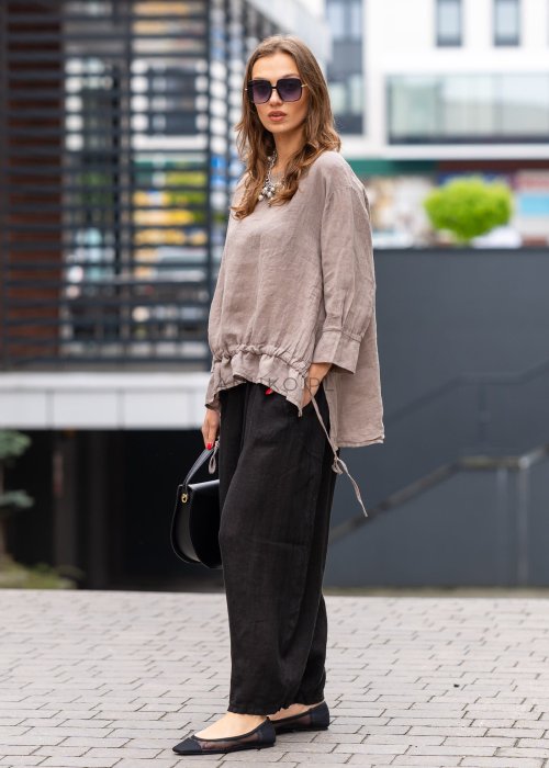 Czarne lniane spodnie damskie z szeroką nogawką i elastycznym pasem ze sznurkiem. Stylizacja casual z lekką bluzką i balerinami w miejskim wydaniu.