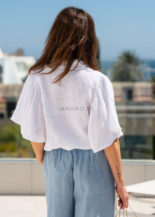 Biała koszula lniana damska o luźnym kroju z szerokimi rękawami i kołnierzykiem. Lekki, naturalny materiał pięknie układa się na sylwetce.