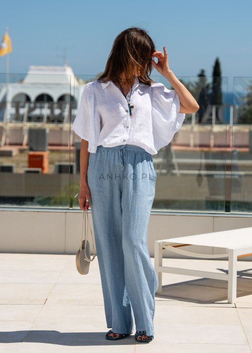 Biała koszula lniana damska o luźnym kroju z szerokimi rękawami i kołnierzykiem. Lekki, naturalny materiał pięknie układa się na sylwetce.