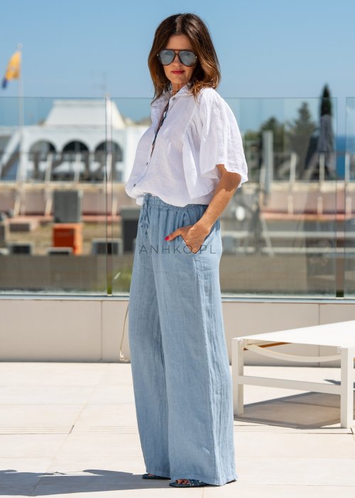 Biała koszula lniana damska o luźnym kroju z szerokimi rękawami i kołnierzykiem. Lekki, naturalny materiał pięknie układa się na sylwetce.