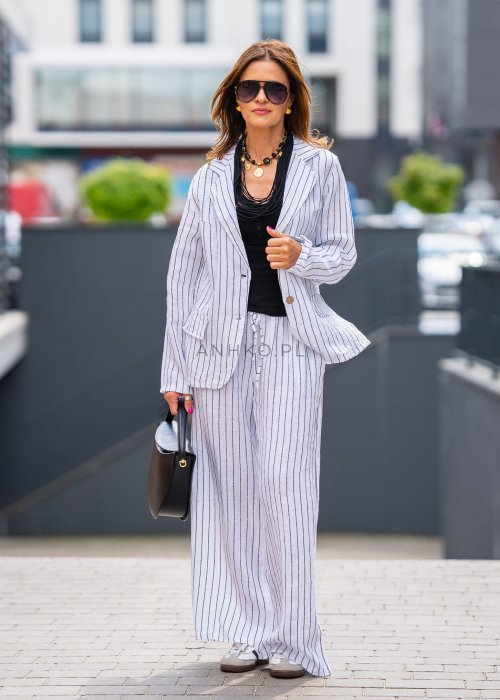 Lniana marynarka damska w białym kolorze w pionowe paski z klasycznymi klapami i drewnianymi guzikami. Stylizacja elegancka z miejskim charakterem.