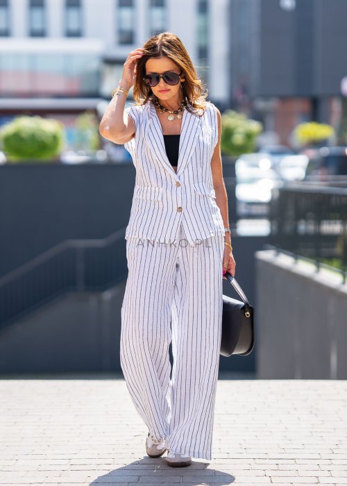 Spodnie lniane damskie w białym kolorze w pionowe paski z szerokimi nogawkami i elastycznym pasem. Stylizacja lekka i elegancka.