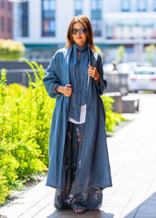 Długie niebieskie kimono lniane oversize z szerokimi rękawami, noszone w stylizacji z jasnym topem i wzorzystymi spodniami. Lekka, maxi narzutka w miejskim looku.