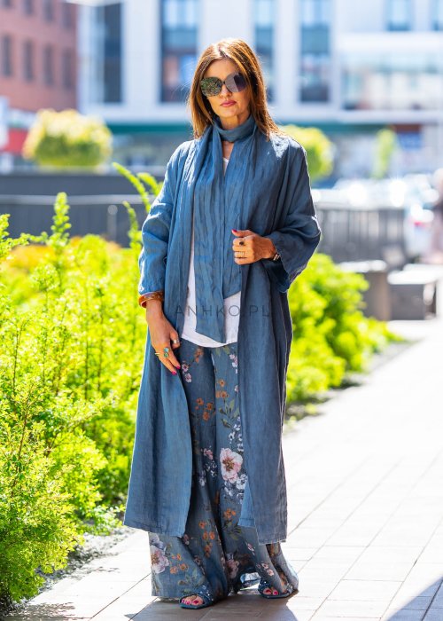 Długie niebieskie kimono lniane oversize z szerokimi rękawami, noszone w stylizacji z jasnym topem i wzorzystymi spodniami. Lekka, maxi narzutka w miejskim looku.