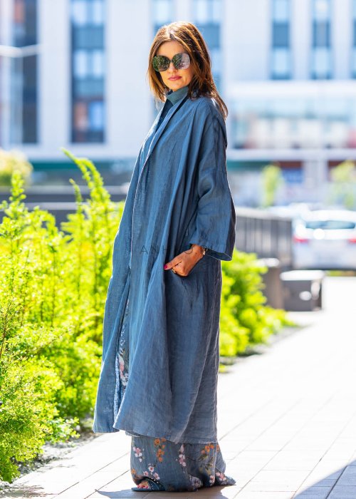 Długie niebieskie kimono lniane oversize z szerokimi rękawami, noszone w stylizacji z jasnym topem i wzorzystymi spodniami. Lekka, maxi narzutka w miejskim looku.